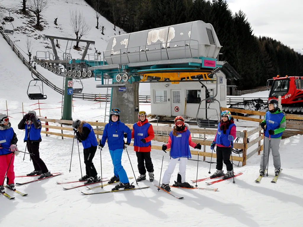 Gruppe steht auf Skiern unter der Talstation des Sessellifts.